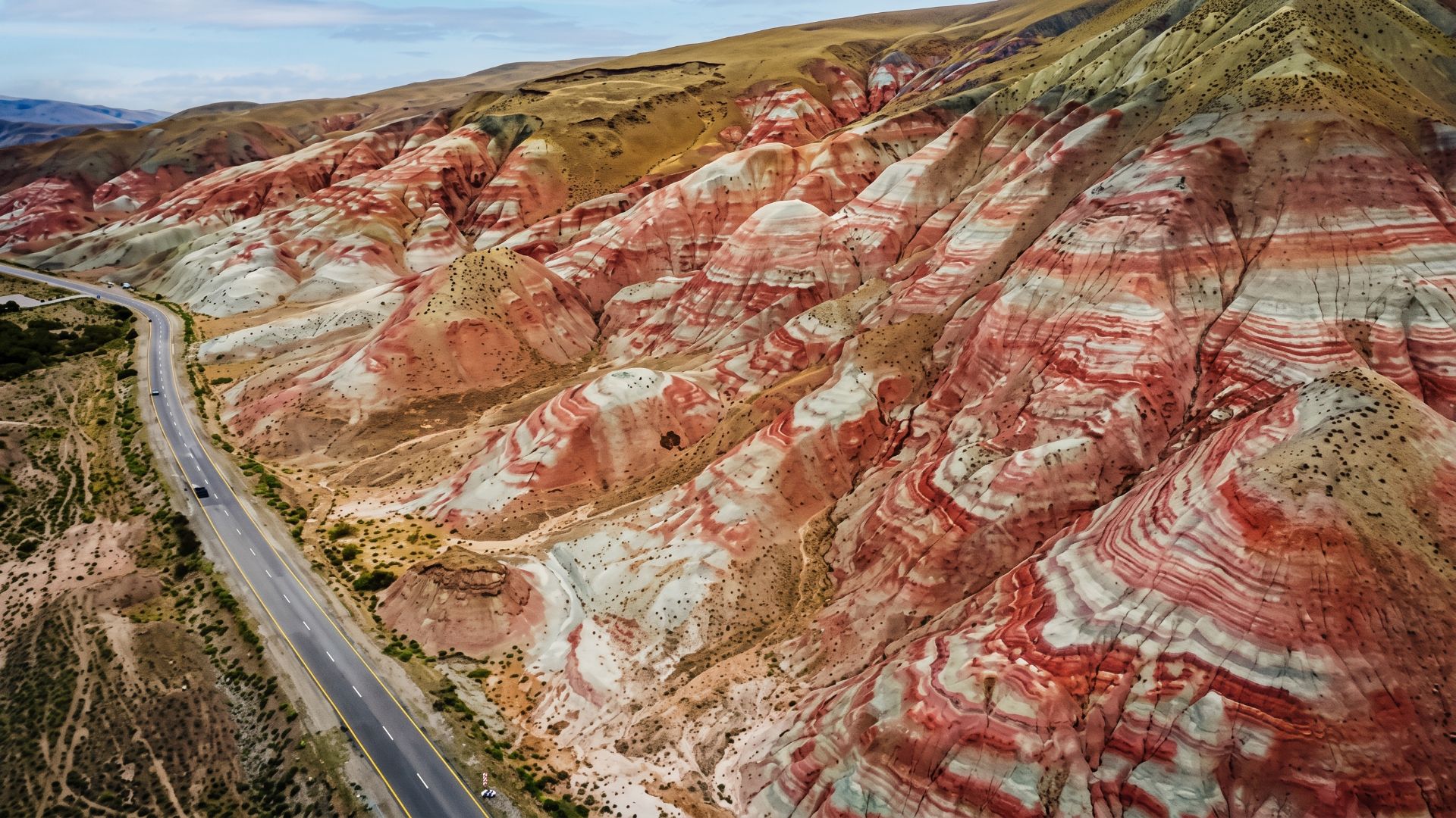 Red and white striped rocky hills beside a road in the supplied Khizi article image